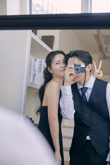 카메라 앞에서 볼에 입 맞추는 두 사람