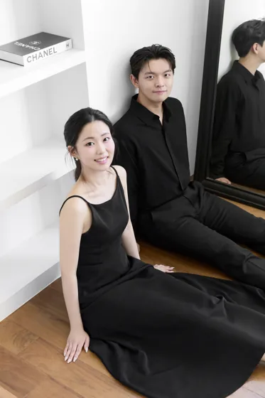 검은 의상을 입고 나란히 앉은 두 사람